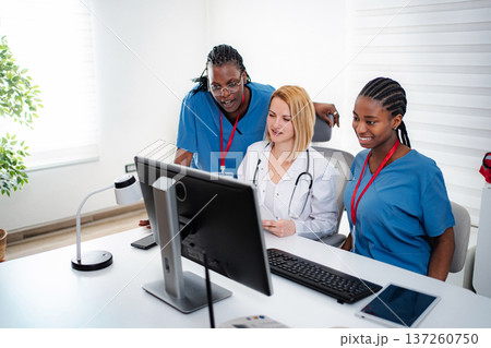 Medical team collaborating on computer in healthcare setting Medical team collaborating on computer in healthcare setting 137260750