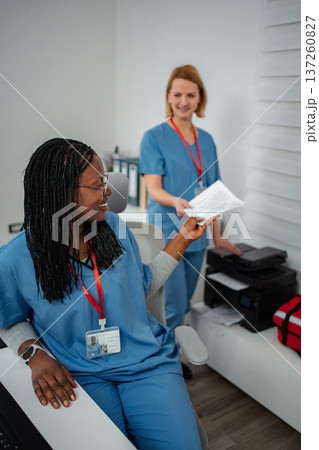 Nurses cooperating in hospital office passing documents to each other 137260827