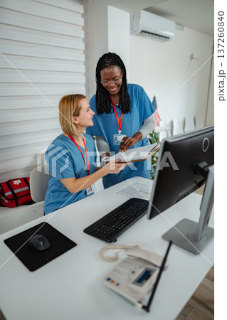 Two nurses collaborating on patient care at a reception desk Two nurses collaborating on patient care at a reception desk 137260840