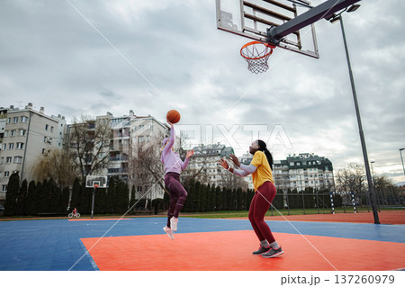 Women playing basketball outdoors on urban court Women playing basketball outdoors on urban court 137260979