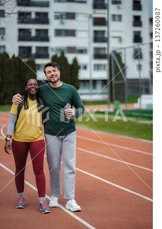 Diverse couple smiling on running track, enjoying fitness together 137260987