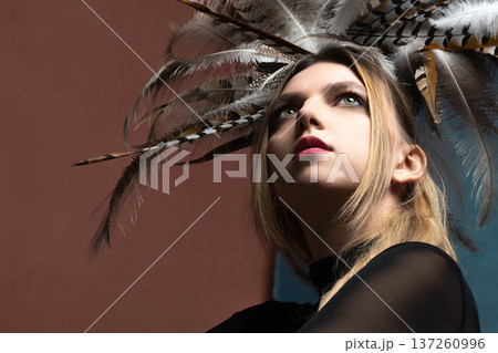 Young woman wearing elaborate feather headdress looking up Young woman wearing elaborate feather headdress looking up 137260996