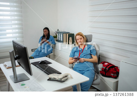 Healthcare workers taking a break using smartphones Healthcare workers taking a break using smartphones 137261388