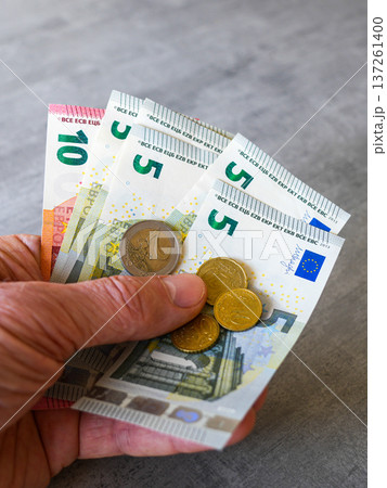 Hand Holding Euro Banknotes and Coins Close Up European Currency Finance Concept 137261400