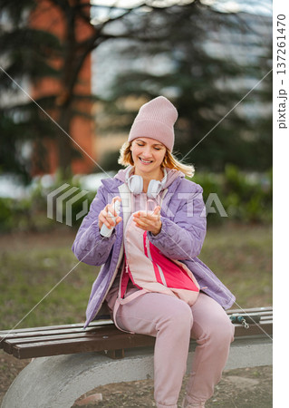 Young woman applying hand sanitizer in a park 137261470