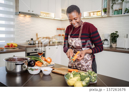 Woman peeling carrot in a bright modern kitchen preparing healthy food Woman peeling carrot in a bright modern kitchen preparing healthy food 137261676