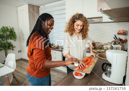 Diverse women friends cooking healthy meal together in kitchen Diverse women friends cooking healthy meal together in kitchen 137261730