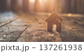 Wooden house figurine on rustic surface with warm sunlight creating a cozy home atmosphere 137261938