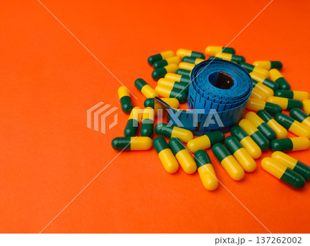 Collection of capsules and a measuring tape on a orange background. 137262002