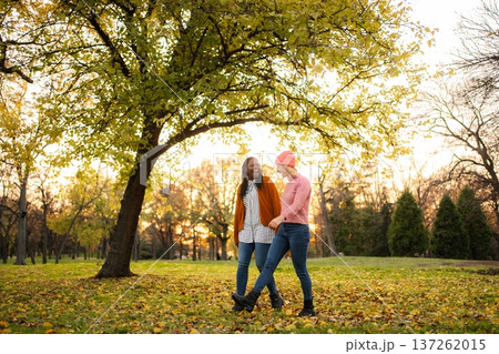 Diverse women friends walking in autumn park Diverse women friends walking in autumn park 137262015