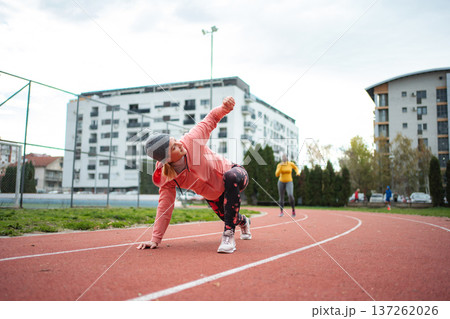 Young adult woman stretching on running track preparing for workout Young adult woman stretching on running track preparing for workout 137262026