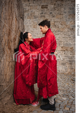 Interracial couple celebrating wedding wearing traditional red Chinese clothing Interracial couple celebrating wedding wearing traditional red Chinese clothing 137262075