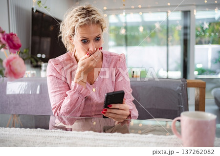 Woman feeling shock and bad news on smartphone at home Woman feeling shock and bad news on smartphone at home 137262082