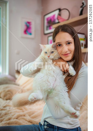 Girl smiling holding fluffy white cat with blue eyes 137262085