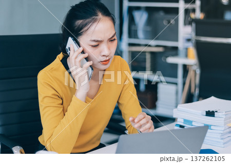 Young professional woman suffering from headache while analyzing financial charts and graphs on computer, experiencing work related stress in modern office Young professional woman suffering from headache while analyzing financial charts and graphs on computer, experiencing work related stress in modern office 137262105