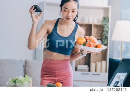 Fit young Asian women in activewear sitting on yoga mat and eating fresh vegetable salad after workout, representing clean eating, fitness lifestyle, wellness routine and health balance. Fit young Asian women in activewear sitting on yoga mat and eating fresh vegetable salad after workout, representing clean eating, fitness lifestyle, wellness routine and health balance. 137262145