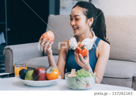 Fit young Asian women in activewear sitting on yoga mat and eating fresh vegetable salad after workout, representing clean eating, fitness lifestyle, wellness routine and health balance. Fit young Asian women in activewear sitting on yoga mat and eating fresh vegetable salad after workout, representing clean eating, fitness lifestyle, wellness routine and health balance. 137262163