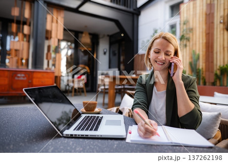 Woman working remotely at cafe making phone call Woman working remotely at cafe making phone call 137262198