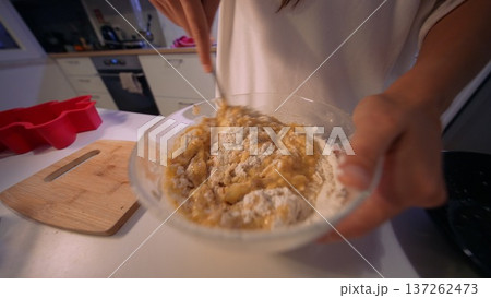 Warm lighting highlights hands blending cookie batter in bowl 137262473