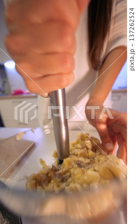 Person prepares mashed potatoes using wooden spoon in home kitchen setting 137262524