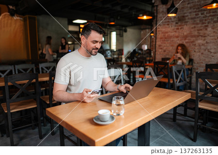 Freelancer working on laptop and using smartphone in cafe 137263135