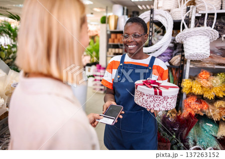 Florist receiving payment for gift box with smartphone in flower shop 137263152