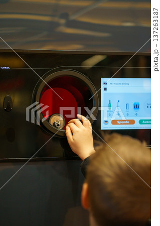 Child placing aluminum can into automated recycling machine. Return system, sustainability, eco responsibility and environmental education concept 137263187