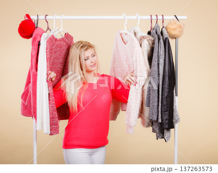 Woman standing in wardrobe picking winter outfit Woman standing in wardrobe picking winter outfit 137263573