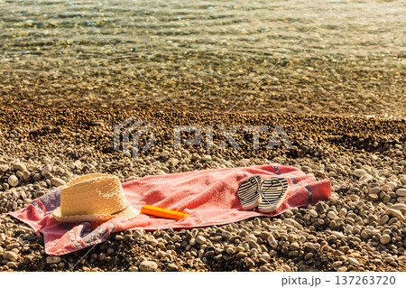 Sun hat and flip flops on stone beach Sun hat and flip flops on stone beach 137263720