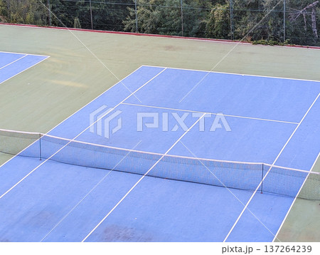 Blue and green tennis court with white lines and net. Sports tourism in mountain village. Blue and green tennis court with white lines and net. Sports tourism in mountain village. 137264239