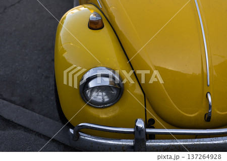 Partial front and side view of yellow retro car with classic headlight detail. Partial front and side view of yellow retro car with classic headlight detail. 137264928