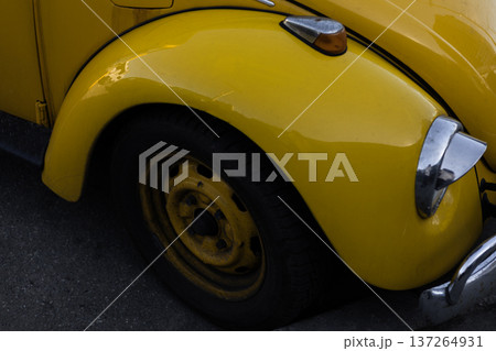 Detail of yellow vintage car front with chrome headlamp and curved body lines. Detail of yellow vintage car front with chrome headlamp and curved body lines. 137264931