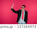 Young person taking smartphone selfie on pink background 137264974