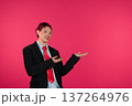 Confident young professional presenting against vibrant pink background 137264976