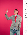 Person taking selfie with smartphone against pink background 137264979
