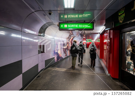 Lyon, france. December 27,2023. Travelers navigate modern lyon metro tunnel with illuminated murals, green exit signs and blurred motion suggesting urban transit journey 137265082