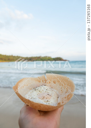 Egg hopper in hand with palm leaf background Egg hopper in hand with palm leaf background 137265168