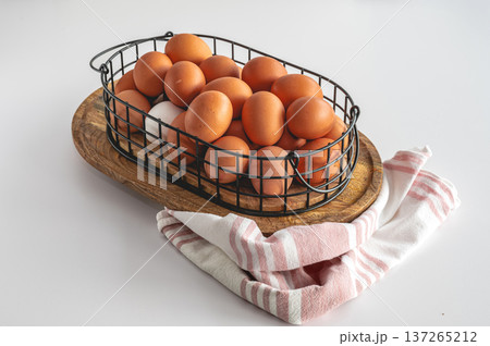 Natural eggs in metal basket against white kitchen background. Natural eggs in metal basket against white kitchen background. 137265212