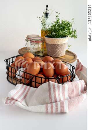 Assorted fresh eggs in metal basket on clean white countertop. Assorted fresh eggs in metal basket on clean white countertop. 137265216