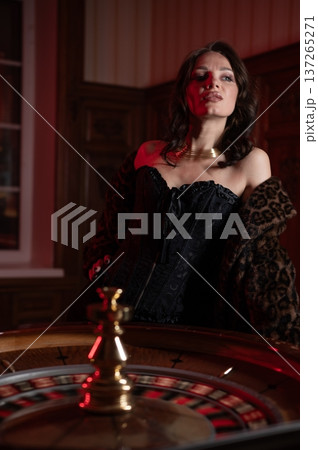 A beautiful brunette in a black dress at the casino roulette wheel.  137265271