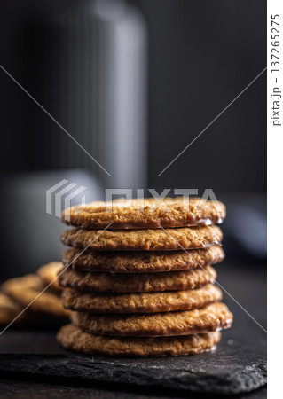 Stack of oatmeal cookies on slate with some placed beside it in a kitchen setting during daylight hours 137265275