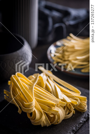 Fresh pasta ready for cooking, showing strands of fettuccine set on a black table. 137265277