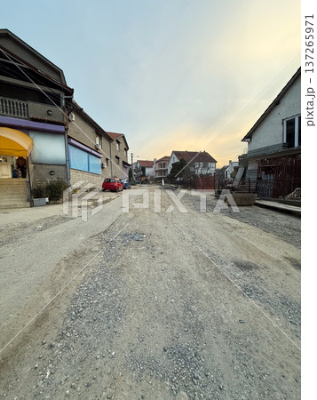 Residential street with damaged asphalt road and visible construction work in suburban neighborhood. Urban infrastructure repair, civil engineering development, municipal maintenance and 137265971