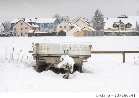 Utility trailer covered in fresh snow in a rural field with residential houses in the background, Emmering, Bavaria, Germany Utility trailer covered in fresh snow in a rural field with residential houses in the background, Emmering, Bavaria, Germany 137266341