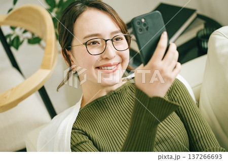自宅のソファーでスマホを見る女性 自宅のソファーでスマホを見る女性 137266693