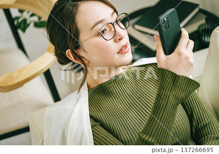 自宅のソファーでスマホを見る女性 137266695