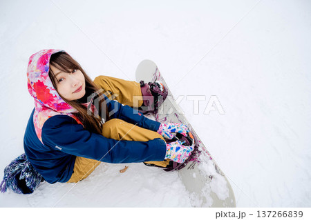 冬にゲレンデでスノーボードを楽しむ若い女性 137266839