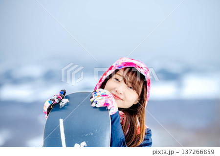 冬にゲレンデでスノーボードを楽しむ若い女性 137266859