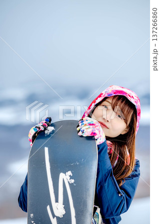 冬にゲレンデでスノーボードを楽しむ若い女性 137266860