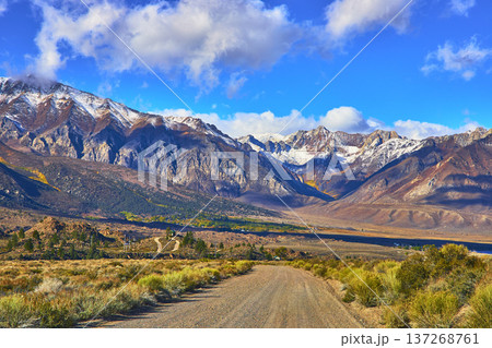Dirt Road Leading to Snow Capped Mountain Range Under Blue Sky Eastern Sierra California 137268761